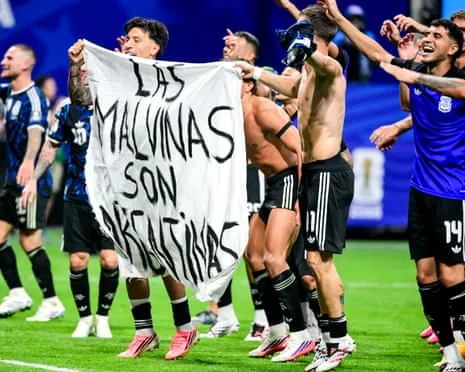 Football players hold up a sheet with the words ‘Las Malvinas Son Argentinas' written on it